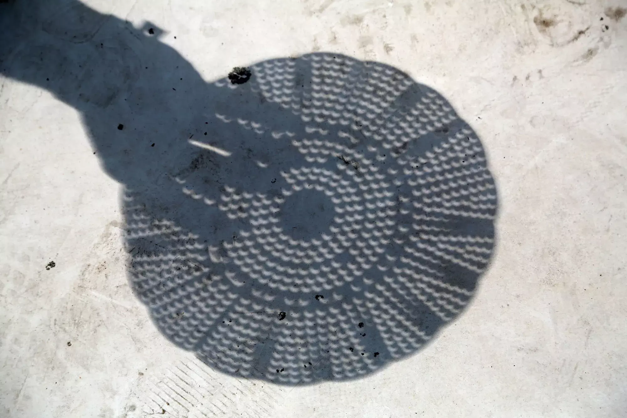 a colander making crescent eclipse shapes