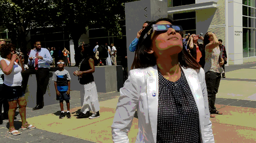 A woman views the eclipse with eclipse glasses.