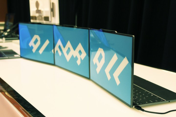 Three of the e-ink lid laptops on a table.