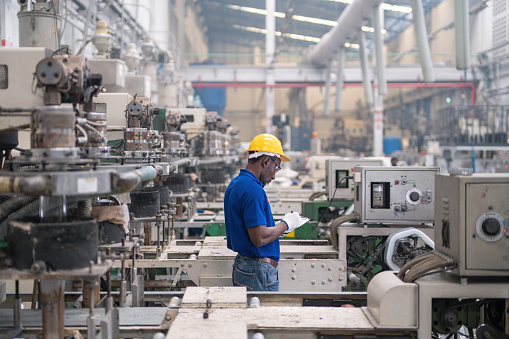 Male manufacturers african working on production line at plastic bag machine