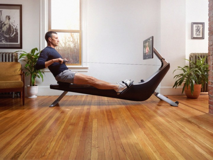 Man using a Hydrow Connected Rower in a room with a hardwood floor.