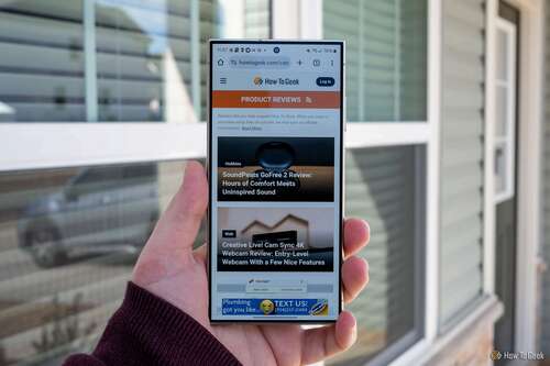 Person holding the Samsung Galaxy S24 Ultra showing the How-To Geek website
