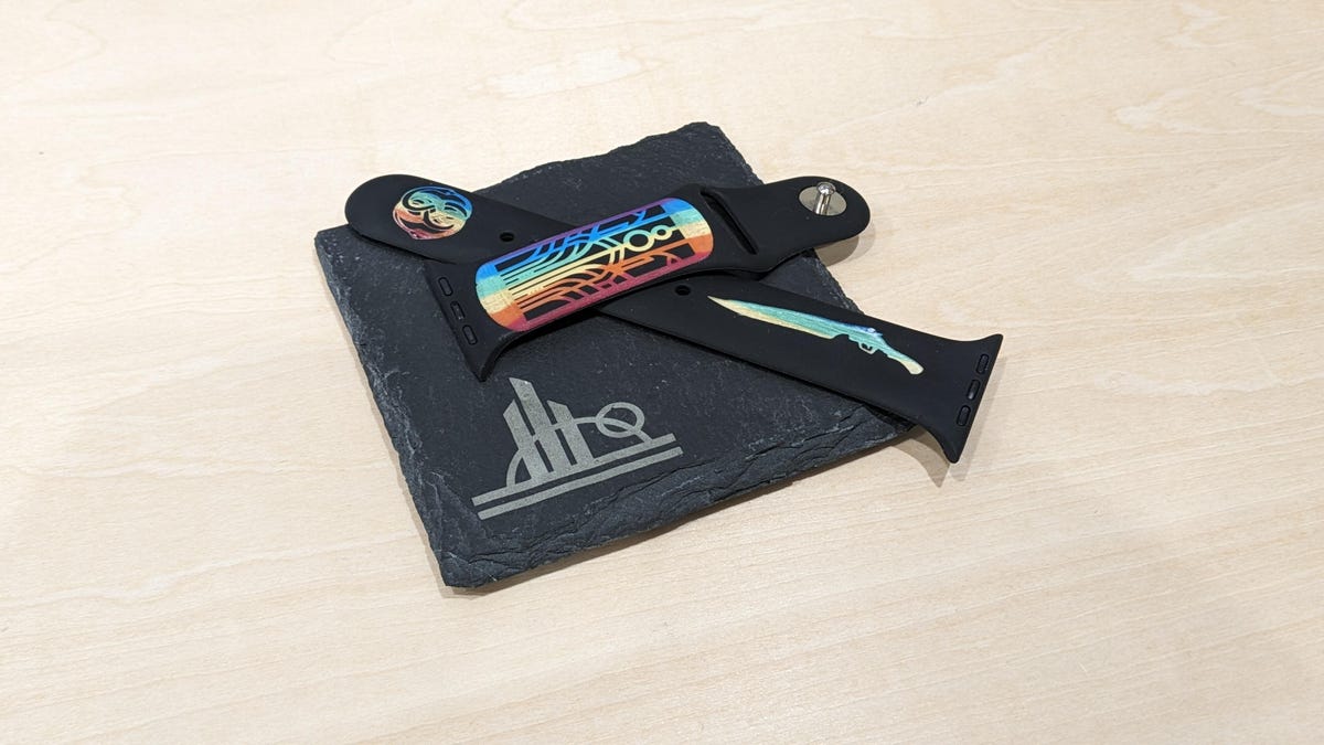 A slate coaster with a Star Wars logo and a watch strap with rainbow etching