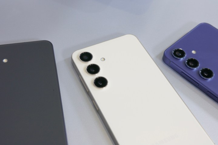 The white Galaxy S24 laying down with the gray and purple S24 next to it.