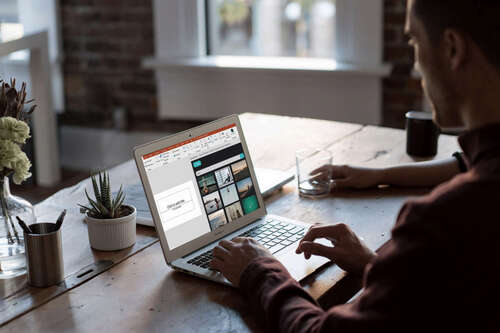 Persons working with MS Powerpoint on a laptop.