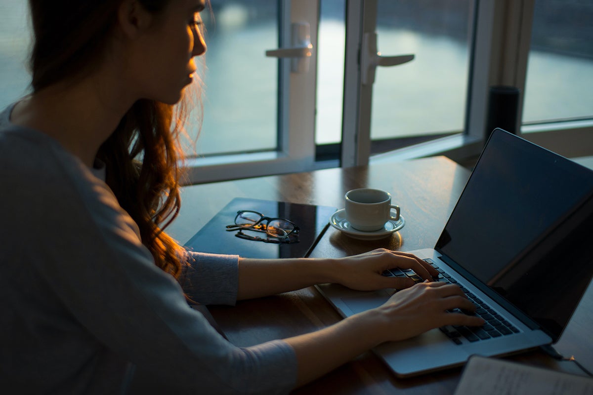 Woman using a laptop on a desk.