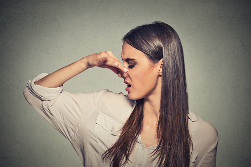 woman pinches nose looks with disgust something stinks