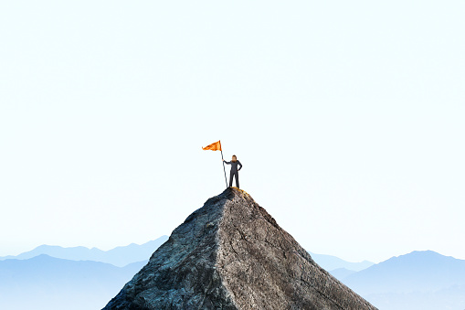 Woman Planting A Flag On A Mountain Peak