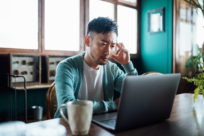 Worried person looking at laptop.