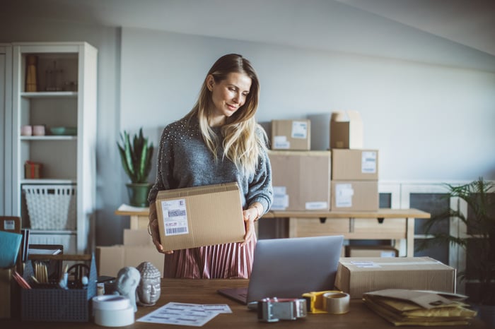 A person in a home office holds a parcel.