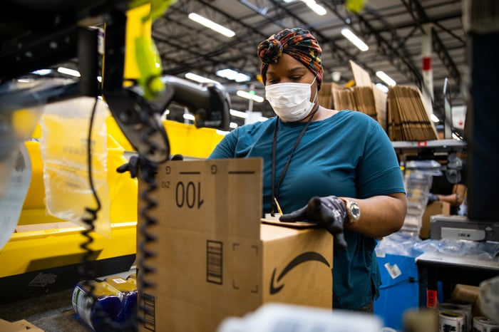 Person packing an Amazon box at a fulfillment center.