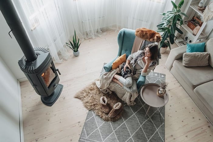 Woman cozy with blanket and slippers in front of fire.