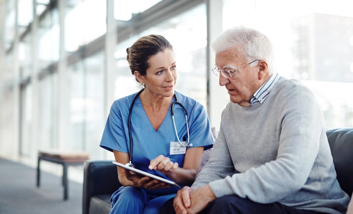 A person in scrubs sitting next to a seated person.