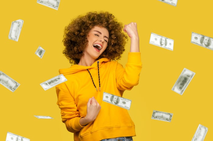 A happy person celebrates while being showered with cash.