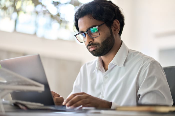 A person at a laptop with a serious expression.