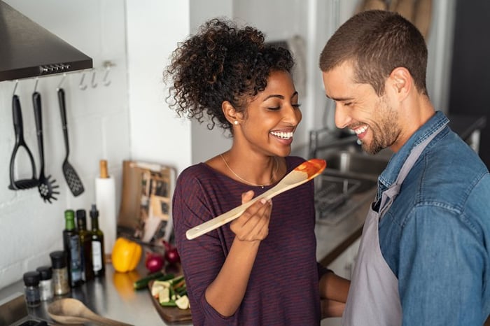 A young couple laughing and cooking at home.