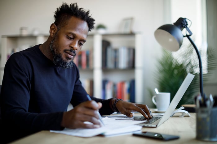 Person sitting at desk writing into a note pad.