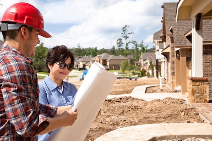 Builder talks to woman at her new home under construction.