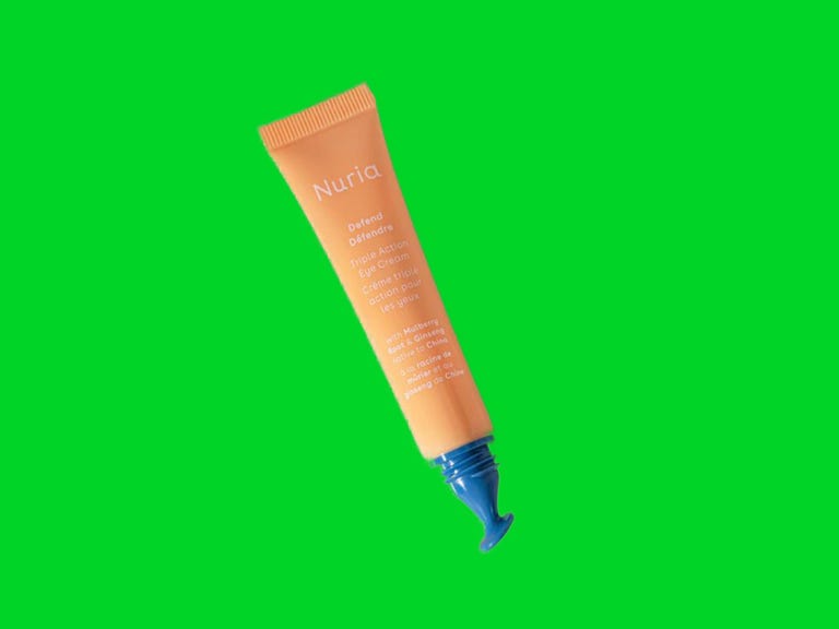 Close up of a pink bottle holding eye cream on a green background