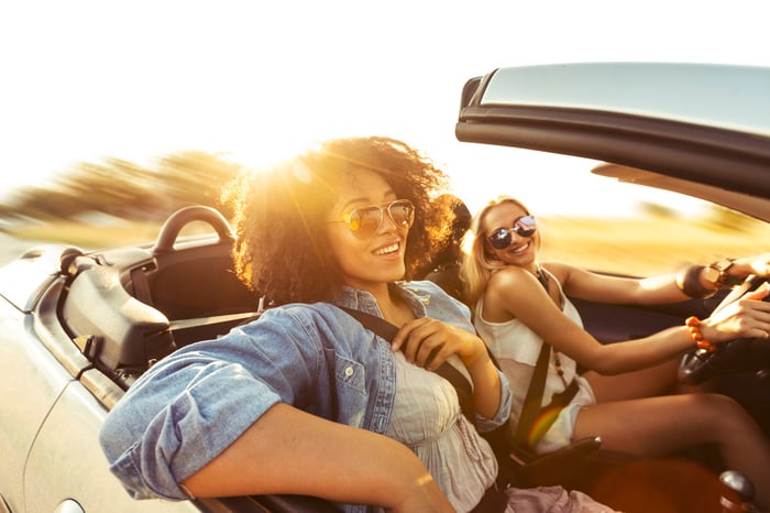 Two friends enjoying a drive in a convertible car with the roof down.