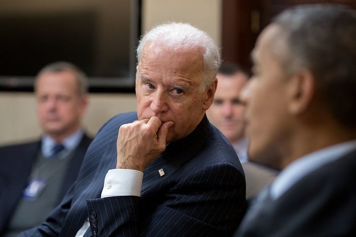 Joe Biden listening to former President Barack Obama speak during a meeting.