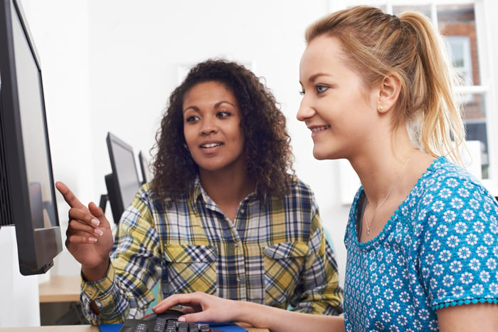 Two people look at a computer monitor.