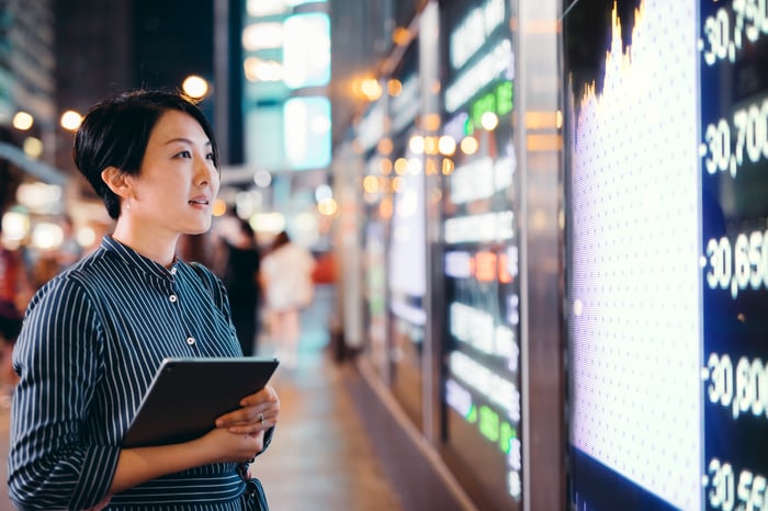 Investor looking at wall of digital trading data.