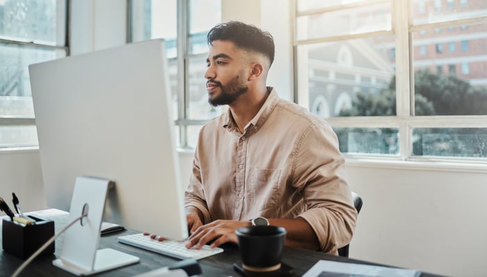 A person at a desk looking at a monitor.