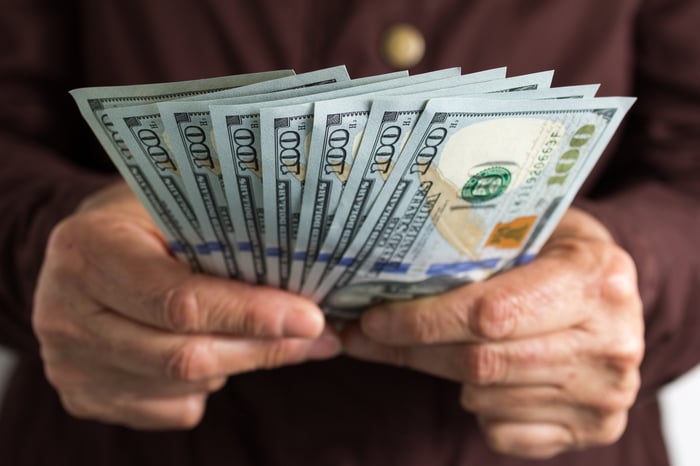 A person holding a fan of $100 bills.