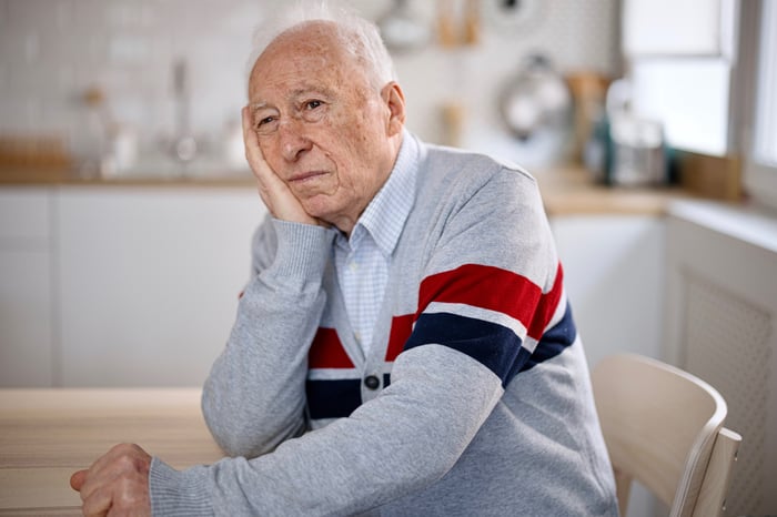 A person at a kitchen table looking sad.