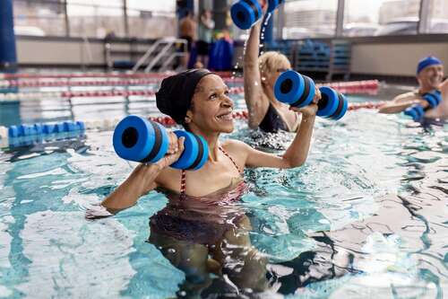 Woman in water exercise class lifting weights.