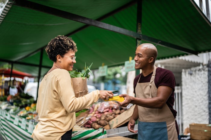 An outdoor vendor takes a digital payment from a phone.