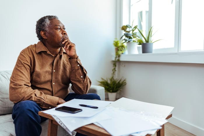 A person at a table full of papers looking toward a window.