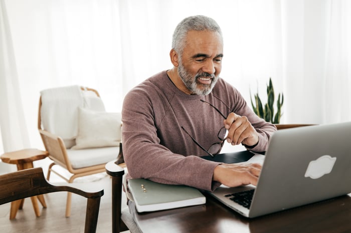 A smiling person at a laptop.