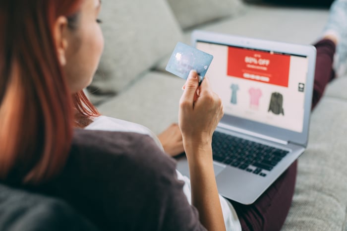 A person holding a credit card and using a laptop.