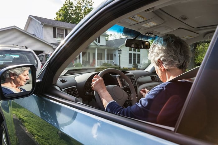 A person pulling their car out of the driveway in front of their house.