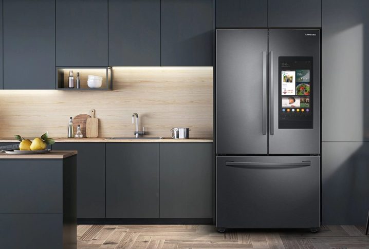 28 cu. ft. Samsung 3-Door French Door Refrigerator with Family Hub in a kitchen with dark gray cabinets and a wooden floor