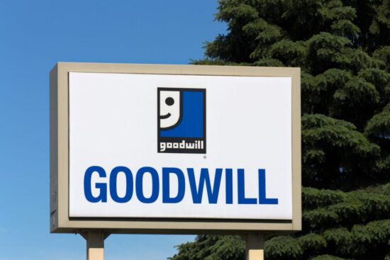 White sign with "Goodwill" written on the bottom and the Goodwill logo on top.