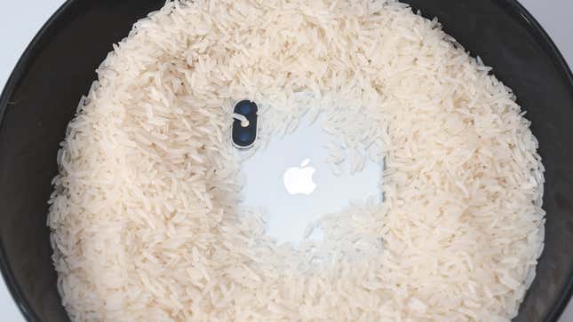 An photo of an iPhone partly submerged in a bowl of rice.