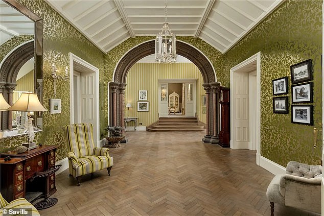 This hallway has more arched doorways, herringbone wood flooring and metallic wallpaper that adds a glamorous feel