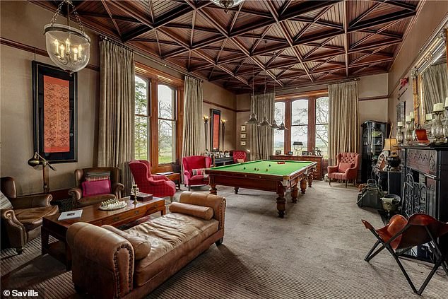 The main house includes this billiards room with a large fireplace and decorative panelled ceiling