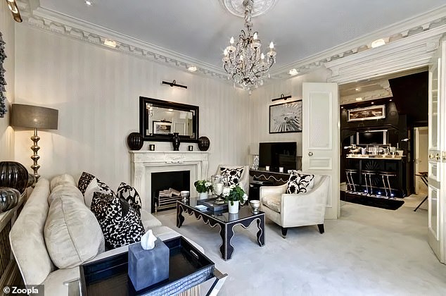 This light-coloured living room leads to a contrasting cocktail bar that is painted black