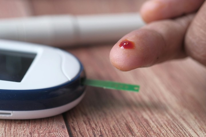 Pinching skin to draw blood for blood glucose analysis.