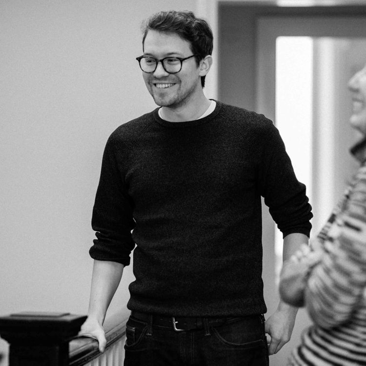 A man wearing a dark jumper stands smiling. He is Andy Brookes, CTO at Faculty.