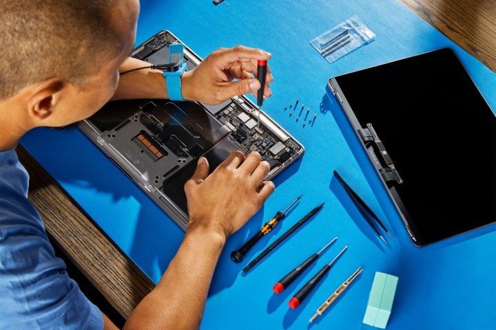 A person repairing a MacBook using Apple's self-service repair kit.