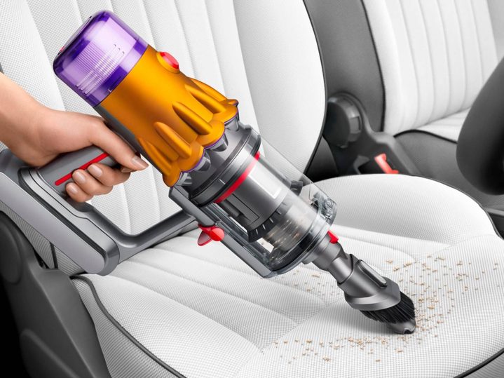 Dyson V12 Detect cordless vacuum being used to clean car interior.