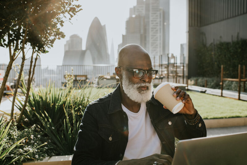 An older person drinking coffee in an urban environment.