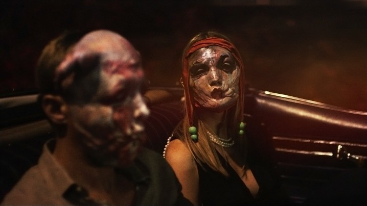 Two people in masks ride in a car in Infinity Pool.