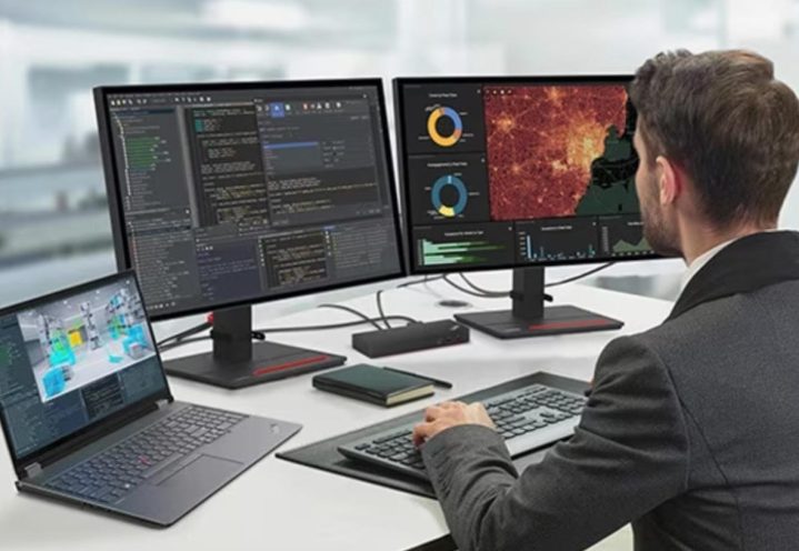 A man works at a Lenovo ThinkPad P16 mobile workstation set up on a desk with two external monitors connected.