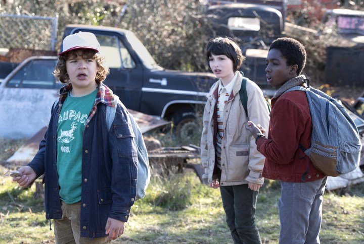 Three boys stand near each other in a junkyard in Stranger Things.